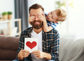 Little boy giving greeting card to dad.