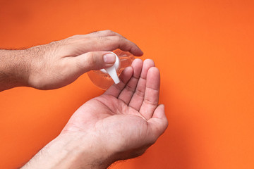 Man hand in container with alcohol gel on the orange background