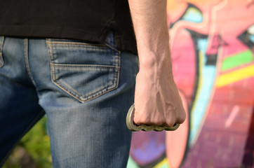 Back view of young caucasian man with brass cnuckle on his hand against ghetto brick wall with...