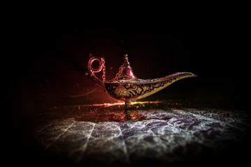 Lamp of wishes concept. Antique Aladdin arabian nights genie style oil lamp with soft light white...
