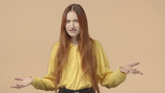Whats wrong with you. Frustrated and confused annoyed redhead woman trying understand, standing puzzled, spread hands sideways say what, dont know, waiting explanation, yellow background