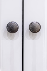 Metal round handles on white doors, close-up