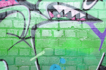 Abstract colorful fragment of graffiti paintings on old brick wall in green colors. Street art...