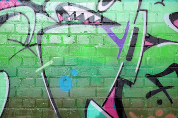 Abstract colorful fragment of graffiti paintings on old brick wall in pink and green colors. Street...