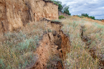 landslide with cracks in the ground, the fracture earth sank down, close up nobody.