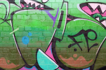 Abstract colorful fragment of graffiti paintings on old brick wall in green colors. Street art...