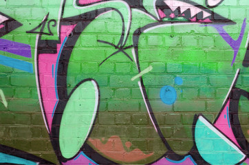 Abstract colorful fragment of graffiti paintings on old brick wall in green colors. Street art...