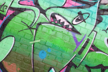 Abstract colorful fragment of graffiti paintings on old brick wall in pink and green colors. Street...