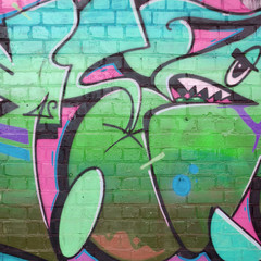 Abstract colorful fragment of graffiti paintings on old brick wall in pink and green colors. Street...