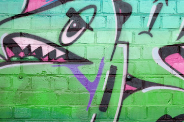 Abstract colorful fragment of graffiti paintings on old brick wall in green colors. Street art...