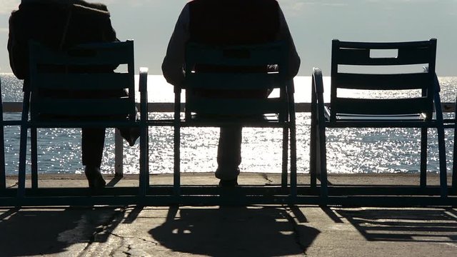 Winter sun gazing on the Promenade des Anglais in Nice, France. People silhouttes.