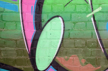Abstract colorful fragment of graffiti paintings on old brick wall in pink and green colors. Street...
