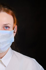 Half face woman in a white shirt and a medical mask on a black background. Concept of people who are isolated in a coronavirus quarantine