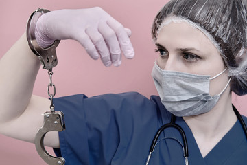 Concept of stay at home. Doctor with a scared face in a medical uniform and handcuffs