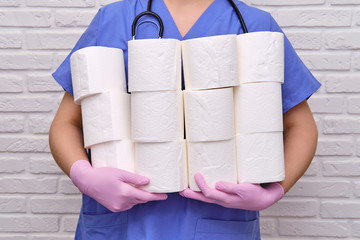 Doctor with rolls of toilet paper in his hands. A nurse holds a lot of rolls of white toilet paper,...