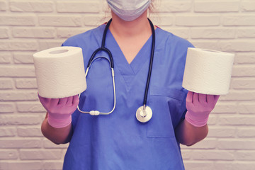 A nurse holds two rolls of white toilet paper. Doctor with a stethoscope with rolls of toilet paper...