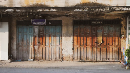 Fototapeta na wymiar Old art wall and door at Lumpang Thailand.Vintage wooden door shop store.Home exterior texture history beautiful.Travel traditional front house architecture building.Landmark town city street