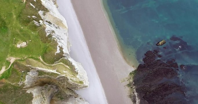 Chalk cliffs of Etretat, Normandy, France with the natural arch of Porte d'Aval and a stone needle called L'Aiguille, shots from the drone, departure of the camera from the cliffs, view of golf course