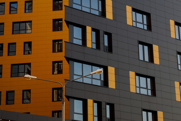 Yellow-brown modern ventilated facade with windows. Fragment of a new elite residential building or...