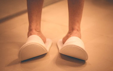 Woman in comfortable slippers on the tiled floor in the bathroom. Hotel shoes.