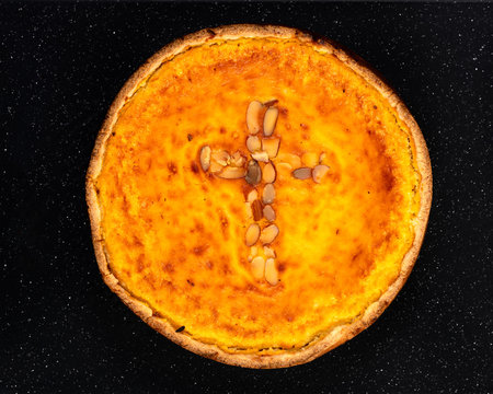 Traditional Romanian cake called Pasca with an almond cross isolated on a black background.
