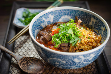 Rice noodles with spicy pork sauce (Nam ngiao) on black table, Thai food.