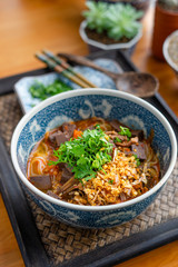 Rice noodles with spicy pork sauce (Nam ngiao) on black table, Thai food.