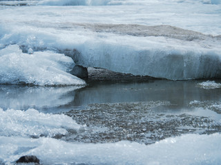 Large, dirty pieces of ice melt in the water and crawl onto each other.