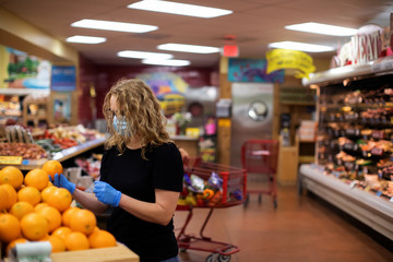 A woman who is looking at products like fruit to buy in a grocery store during the pandemic...