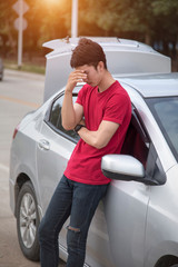 A young man wearing a red shirt is stressed at a car on a highway, Young Asia man having trouble with his broken car