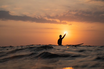 silhouette of a man surfing at sunset in the ocean