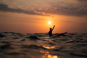 silhouette of a man surfing at sunset in the ocean - obrazy, fototapety, plakaty