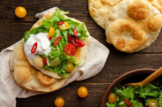 Navajo fried bread with green salad and yougurt on wooden background