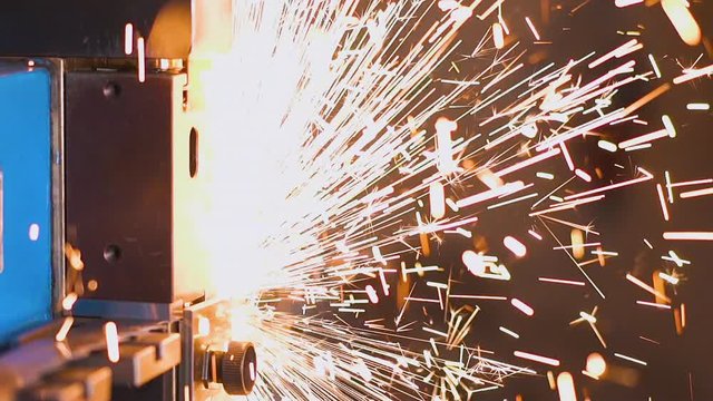 CU shot, macro view: special machine tool welds parts of long metal band saw in sparks shower in plant workshop extreme close view slow motion
