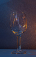 glass of wine one in front of the other with orange light on one side and blue light on the other side of wine glasses