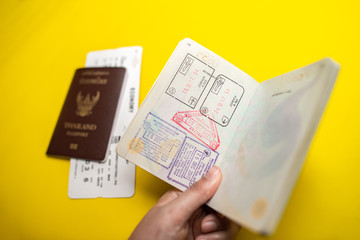 immigration stamps on passport and Thai passport with Plane economy ticket background.