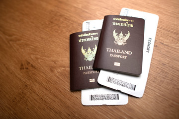 A foreign passport of Thailand with a plane ticket is placed on a wooden table.