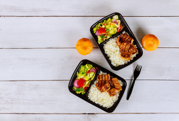 Ready meal to eat on food container with drink and orange.