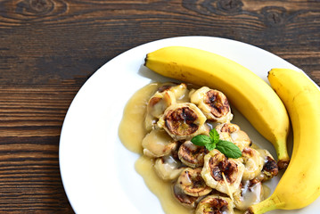 Grilled Bananas With Coconut- Caramel Sauce with fresh bananas on bamboo mat. Banana Thai Dessert menu.