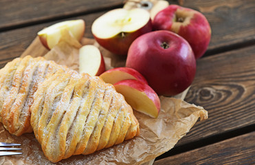Easy Apple Turnovers (German name is Apfeltaschen) on brown paper with fresh red apples on wooden...