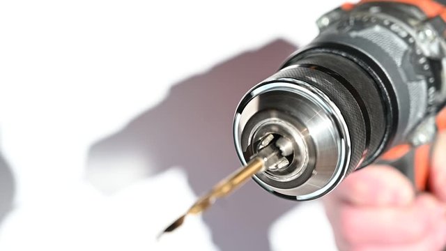 Hand holding metal keyless chuck on an impact driver with drill bit