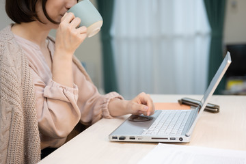 飲み物を飲みながら在宅勤務をする女性