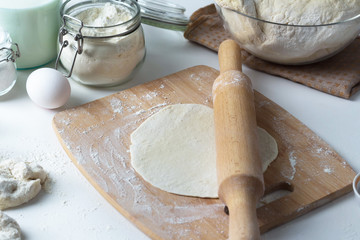 griddle-cake and rolling pin lies on a wooden board, next to flour, eggs, milk. Slovenian dishes, Russian cuisine