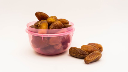 Dates or kurma in purple plastic container on isolated white background.