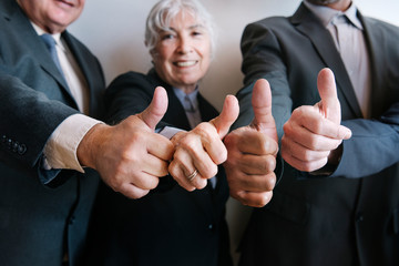 Senior business people giving thumbs up