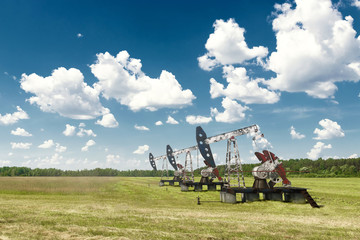 Fototapeta premium Oil pump, oil rig an industrial oil production standing in the field. Technology concept, fossil energy sources, hydrocarbons. Mixed media copy space