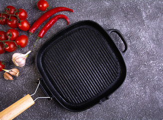empty grill pan, tomatoes, peppers, garlic, on a dark textured background