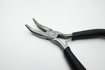 Curved nose pliers. Steel with black handles. Close up on white background.