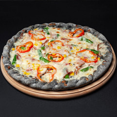 Delicious pizza served on a wooden plate isolated on black