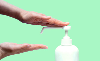 女性の手と消毒用ボトルとコピースペースと水色背景　女性が手を消毒するところ